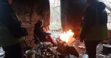 Na zdjęciu miejsce przebywania osób w kryzysie bezdomnościi, jedna osoba siedzi na krześle, obok niej ognisko