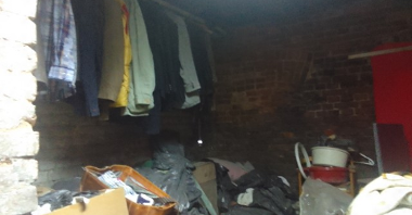 Na zdjęciu miejsce przebywania osób w kryzysie bezdomności. Widać półki ubrania oraz rzeczy codziennego użytku