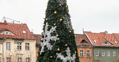 Galeria zdjęć przedstawia choinkę bożonarodzeniową udekorowaną lampkami i bombkami.