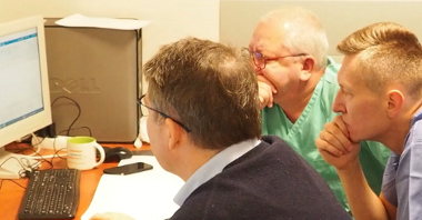 Na zdjęciu trzech lekarzy patrzących w monitor