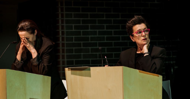 Na zdjęciu dwie kobiety za mównicami, kadr ze spektaklu