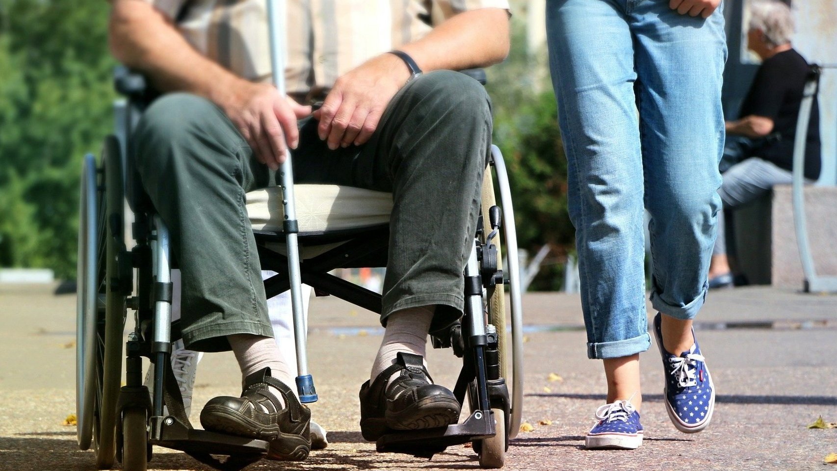 Zdjęcie przedstawia osobę na wózku inwalidzkim i stojące obok dziecko - grafika artykułu