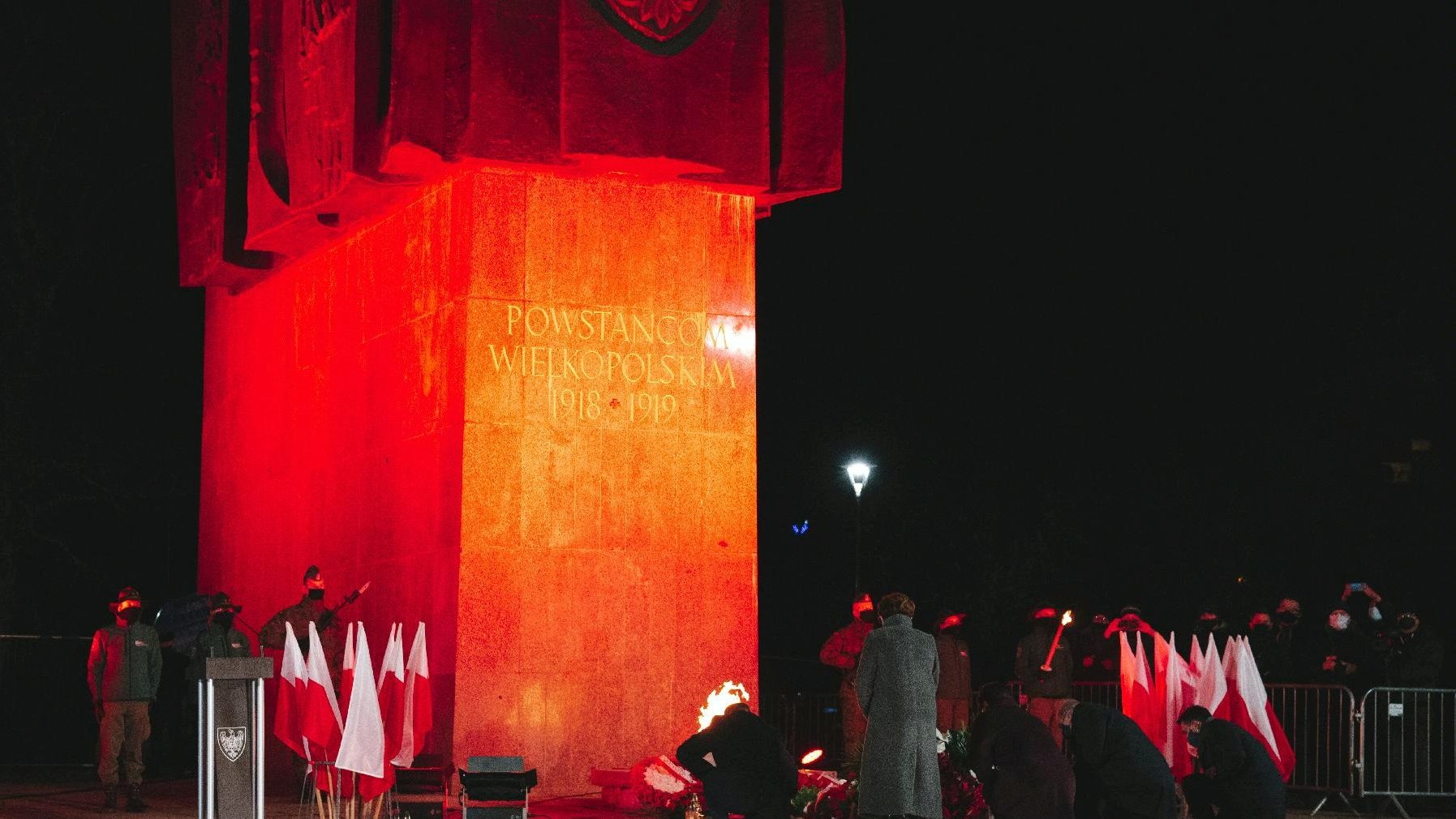 Zdjęcie przedstawia pomnik Powstańców Wielkopolskich i ludzi składającyh pod nim kwiaty. - grafika artykułu