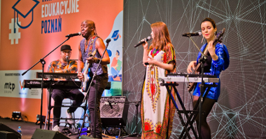 Zdjęcie przedstawia muzyków z instrumentami na scenie - dwie kobiety i dwóch mężczyzn.