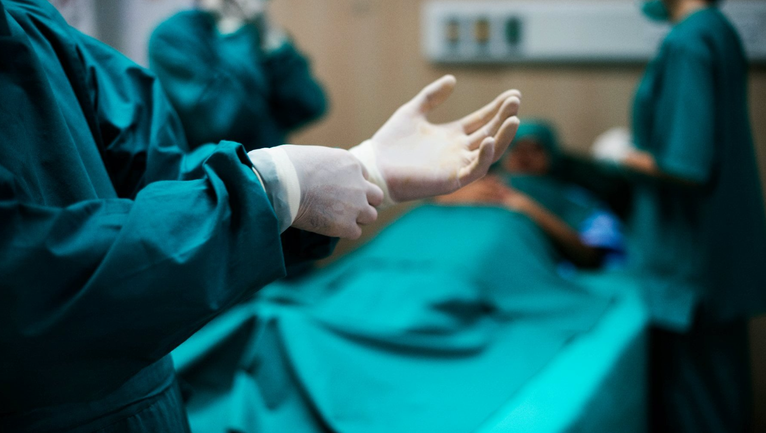 Na zdjęciu sala operacyjna, widać ręce lekarza przygotowującego się do zabiegu - grafika artykułu