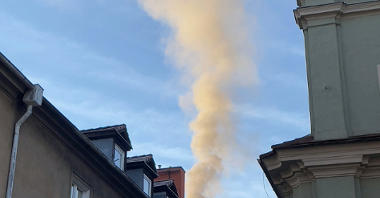 Zdjęcie przedstawia dymiący komin.