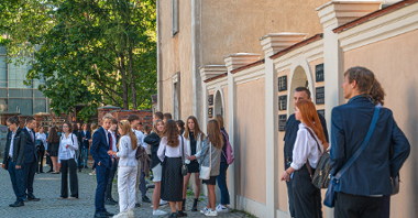 Zdjęcie przedstawia uczniów stojących przed szkołą.