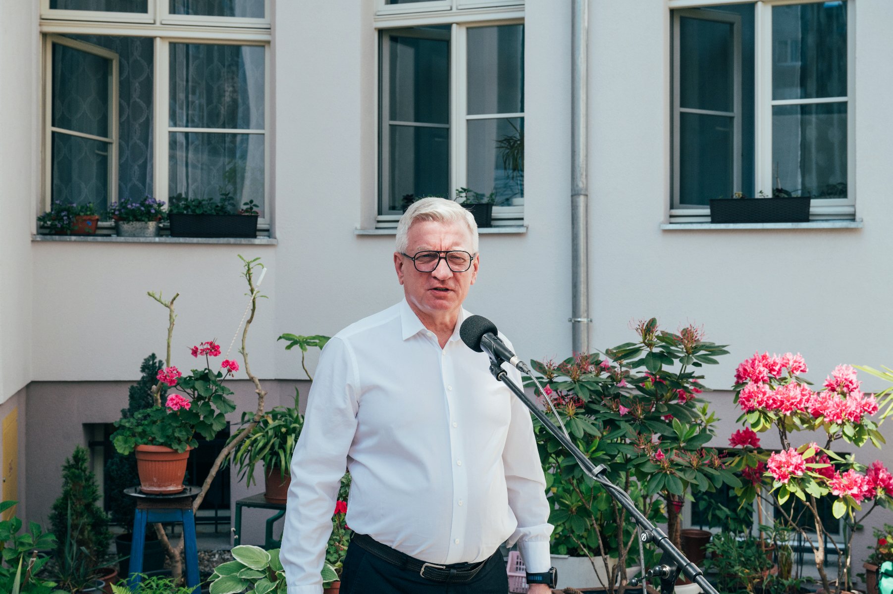 Na zdjęciu prezydent Poznania przed mikrofonem na podwórku - grafika artykułu