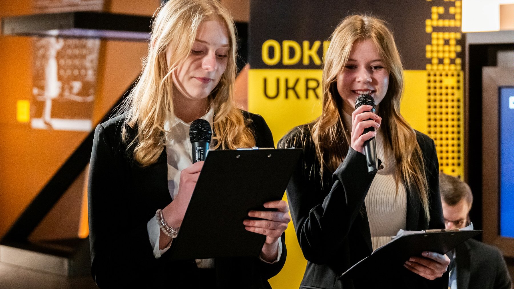 Zdjęcie przedstawia dwie młode dziewczyny trzymające mikrofony.