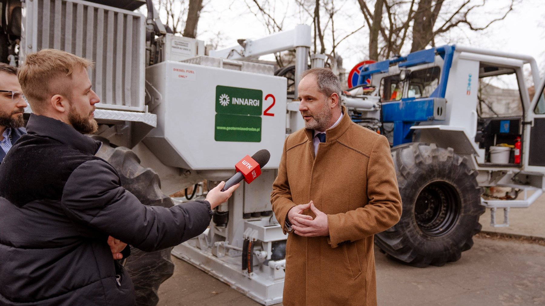 Na zdjęciu mężczyzna rozmawiający z mediami, w tle cieżarówka