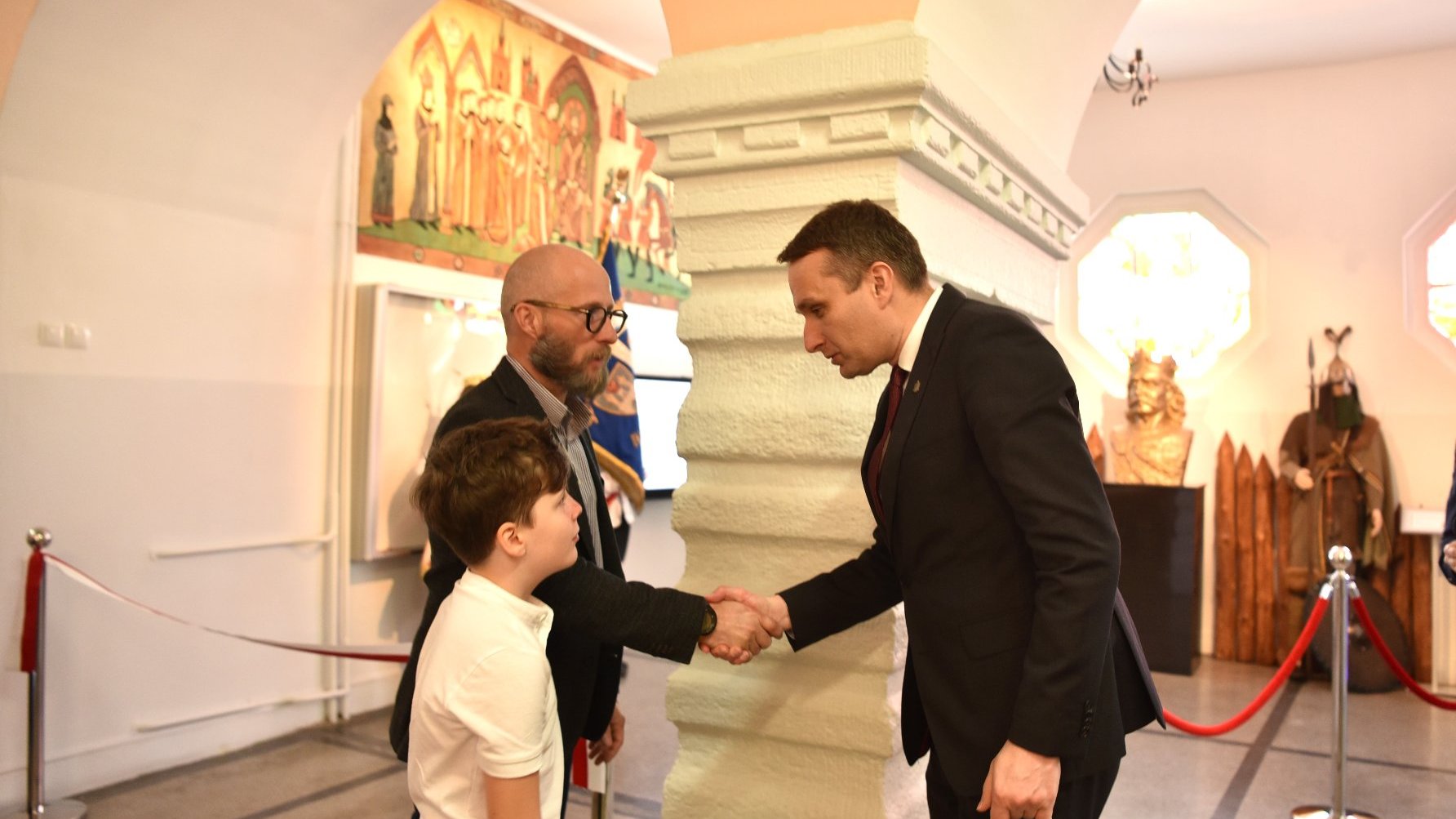 Zdjęcie przedstawia wiceprezydenta ściskajacego dłoń mężczyzny. Obok stoi chłopiec.