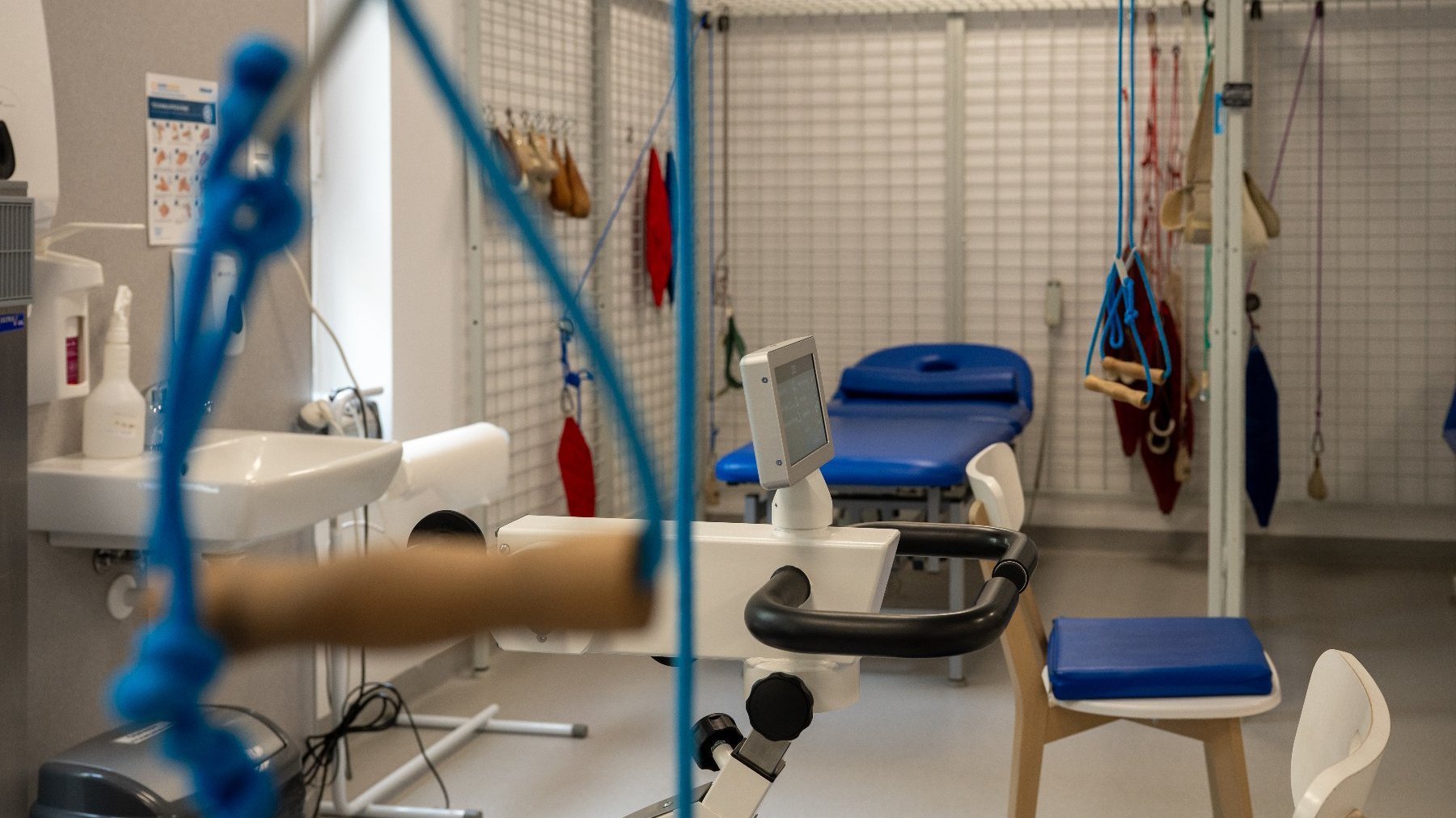 Na zdjęciu sala ze sprzętem do rehabilitacji, w tle łóżko