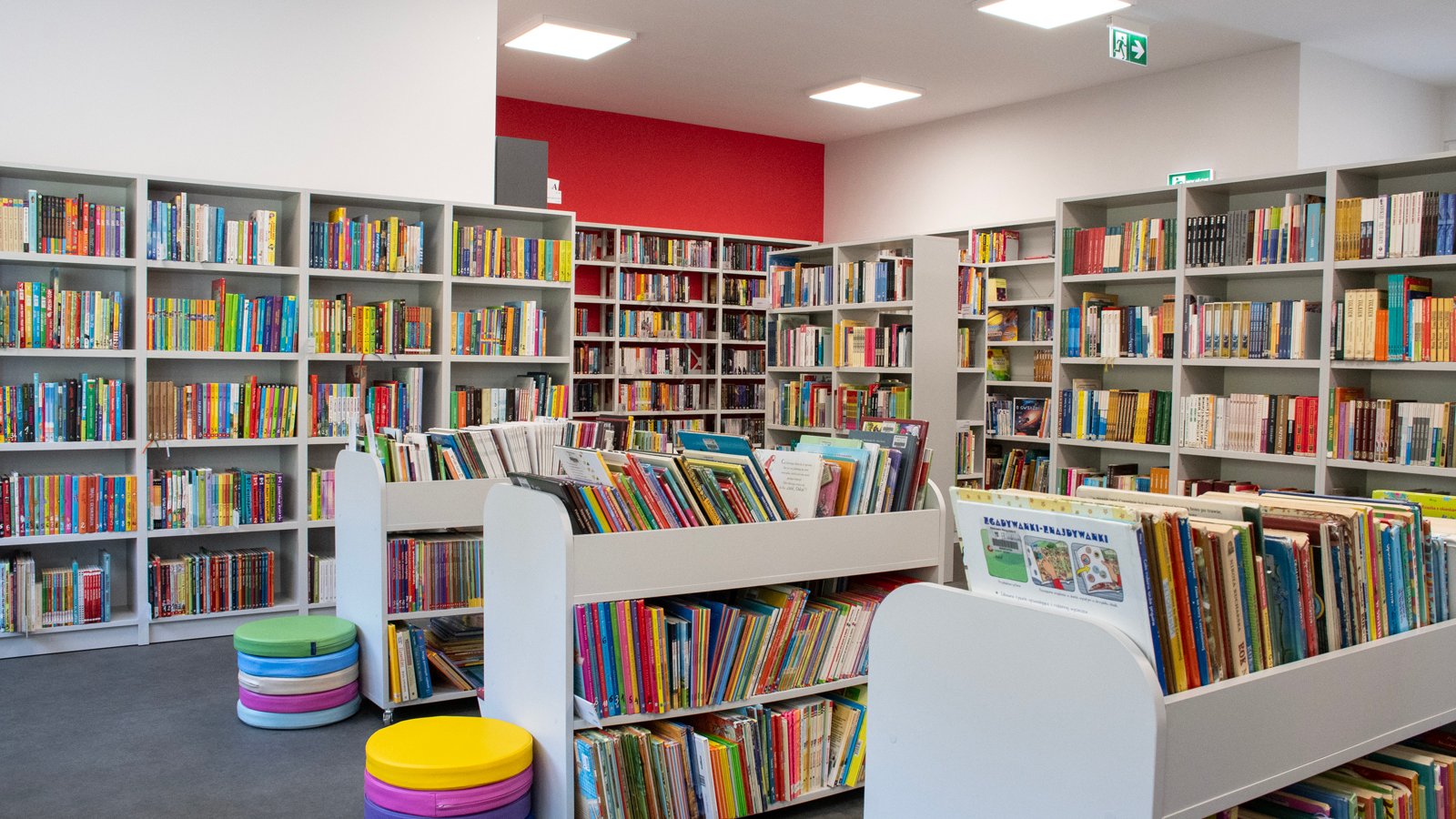 Zdjęcie przedstawia wnętrze biblioteki. Widać na nim półki z książkami.