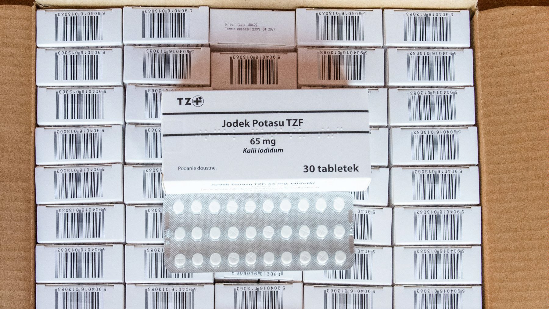 Na zdjęciu karton pełen opakowań tabletek, na nich leży puste opakowanie i blister leku
