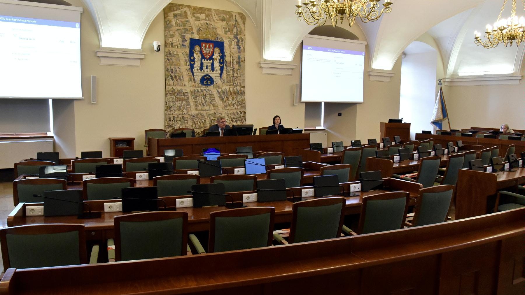 Sala sesyjna. Krzesła radnych są puste, na swoim miejscu siedzi tylko Grzegorz Ganowicz, przewodniczący rady oraz jego zastępczyni - grafika artykułu