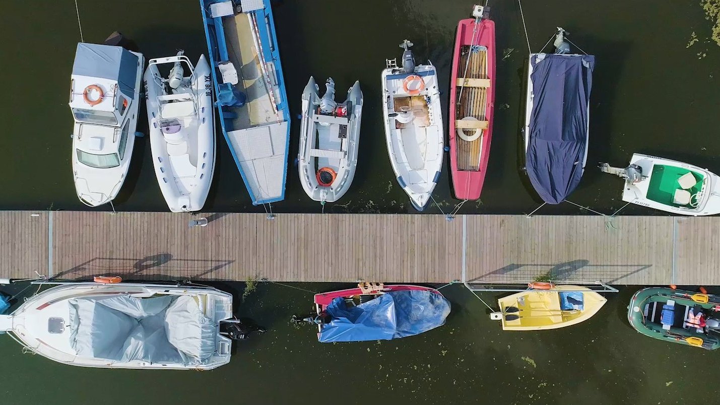Zdjęcie z drona, na którym widać pomost i przycymowane do niego łodzie.
