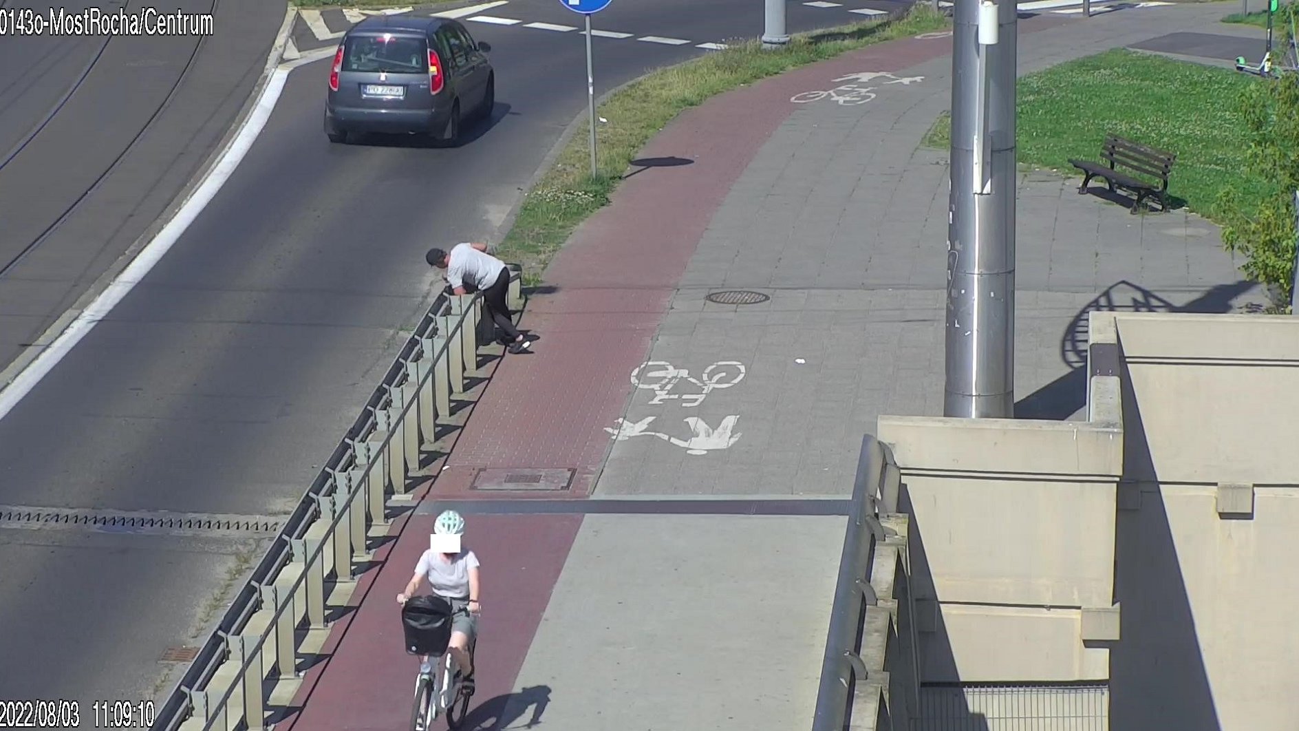 Zrzut ekranu z monitoringu miejskiego, przedstawia osobę pod wpływem alkoholu, która próuje przejść przez barierki odgradzające chodnik od jezdni.