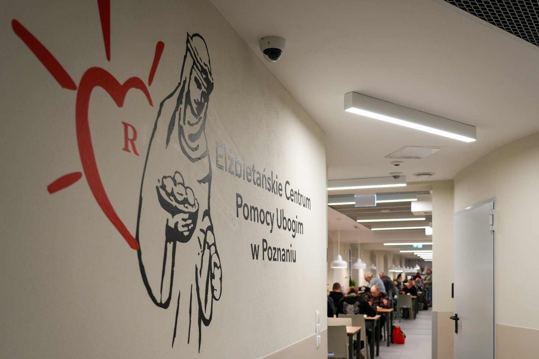 Zdjęcie przedstawia kobietę nakładającą jedzenie do słoika. W misce przed nią znajdują się pokrojony groszek i marchewka.