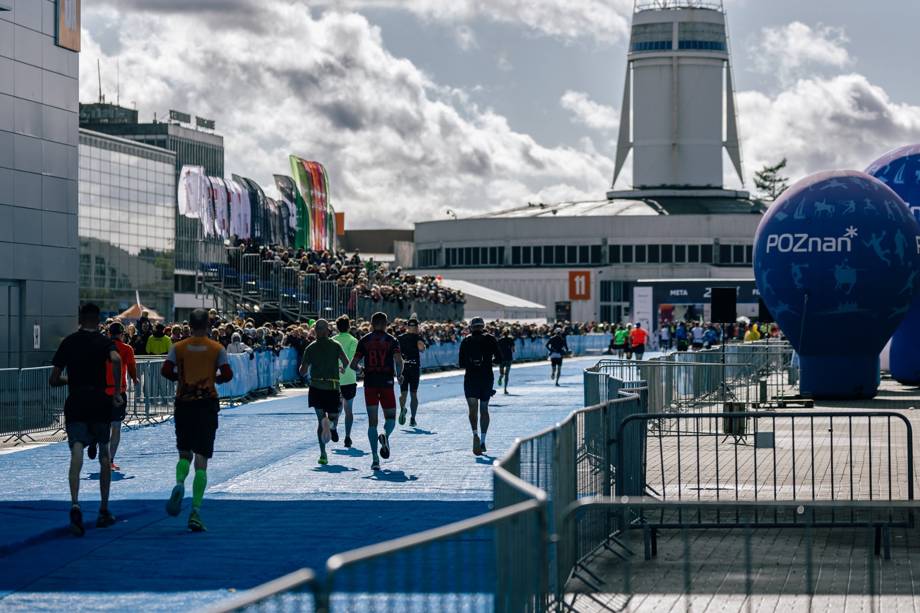 Zawodnicy tegorocznego LOTTO 24. Poznań Maratonu pobiegną zupełnie nową trasą/ fot. K. Szada - Borzyszkowski Zdjęcie przedstawia zawodników wbiegających na teren Międzynarodowych Targów Poznańskich.