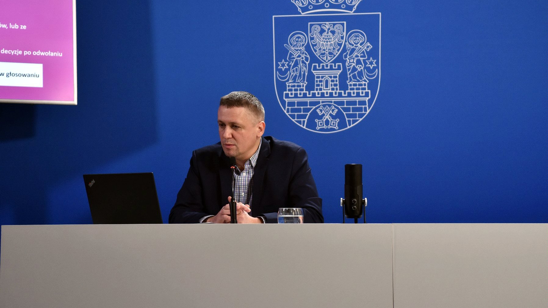 Na zdjęciu dyrektor gabinetu prezydenta Poznania na niebieskim tle