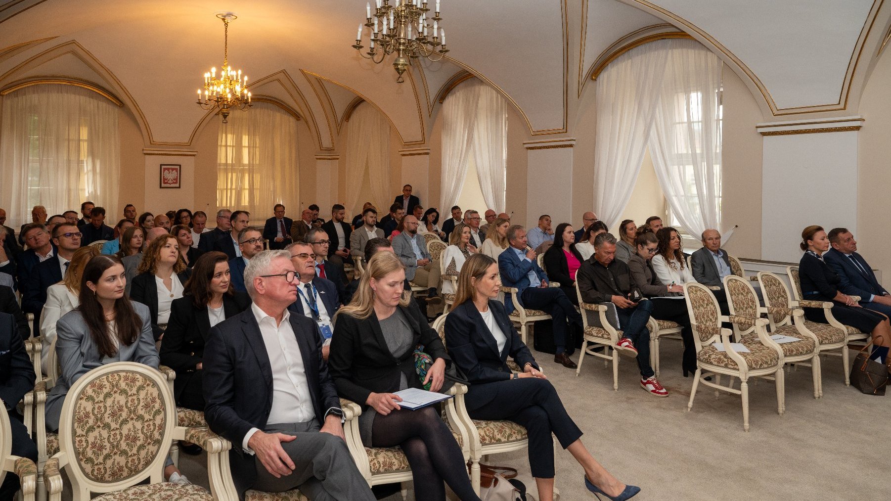 Sala Biała Urzędu. Tłum ludzi siedzi i słucha przemówień.