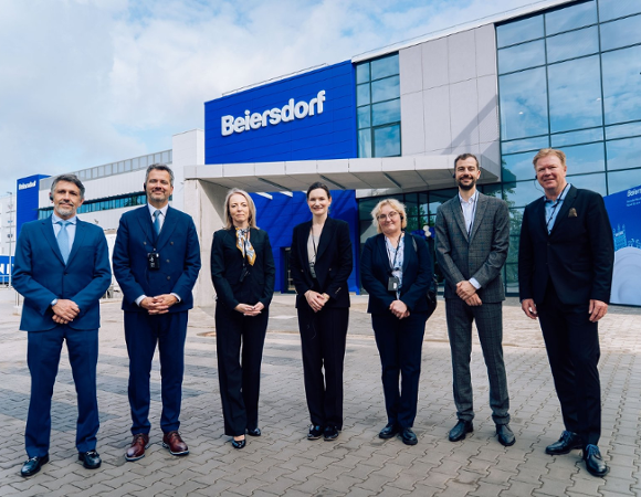 Przedstawiciele Beiersdorf pozują razem z panią prezydent Natalią Weremczuk. W tle fabryka Beiersdorf.