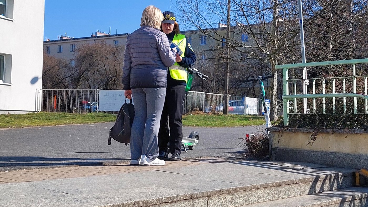 strażniczka przekazuje materiały informacyjne i odblaskową opaskę
