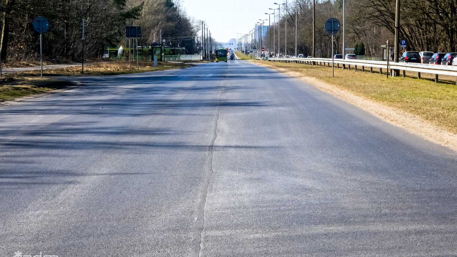 Równa asfaltowa nawierzchnia ul. Warszawskiej po remoncie, po bokach zieleń