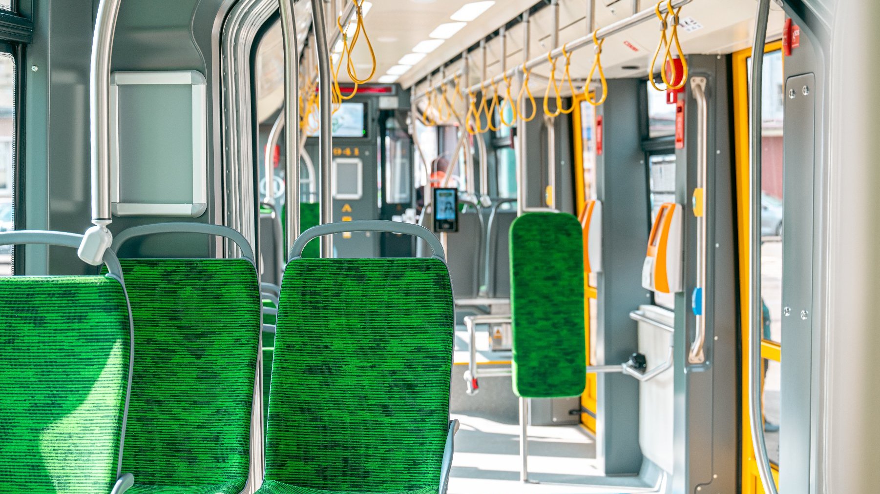 Wnętrze tramwaju, widać zielone siedzenia