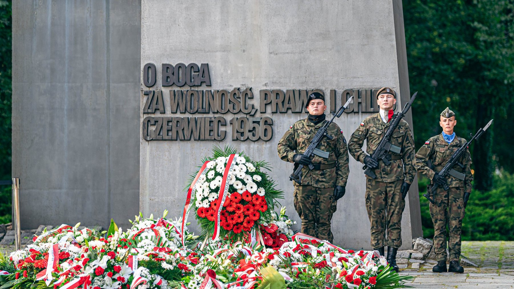 Na zdjęciu pomnik Poznańskiego Czerwca, pod nim kwiaty, obok stoją żołnierze na warcie