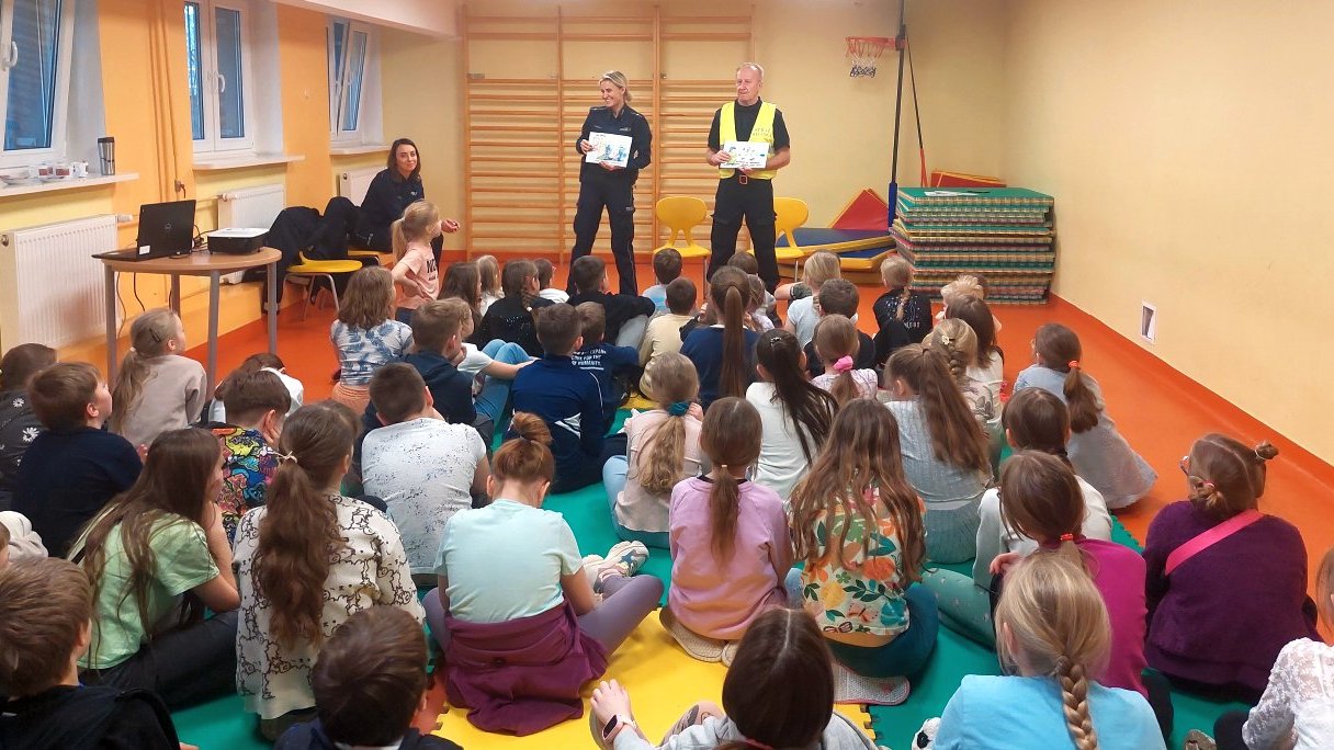 funkcjonariusze omawiają bezpieczne zachowania w sytuacjach przedstawionych na planszach