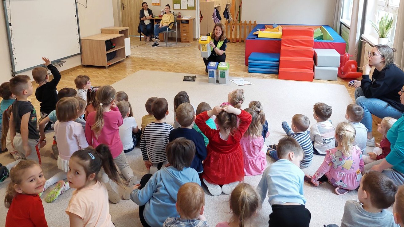 strażniczka przedstawia pojemniki do segregacjoi odpadów