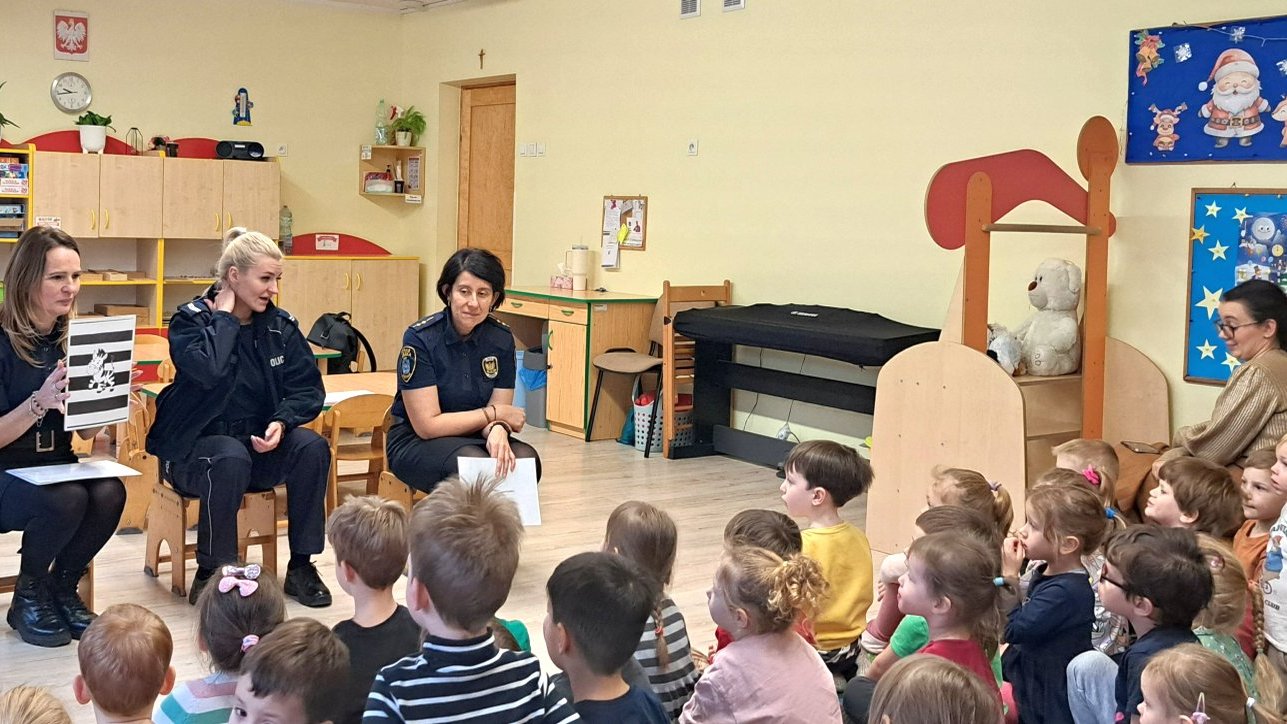 strażniczka prezentuje planszę ilustrującą omawianie przejścia dla pieszych