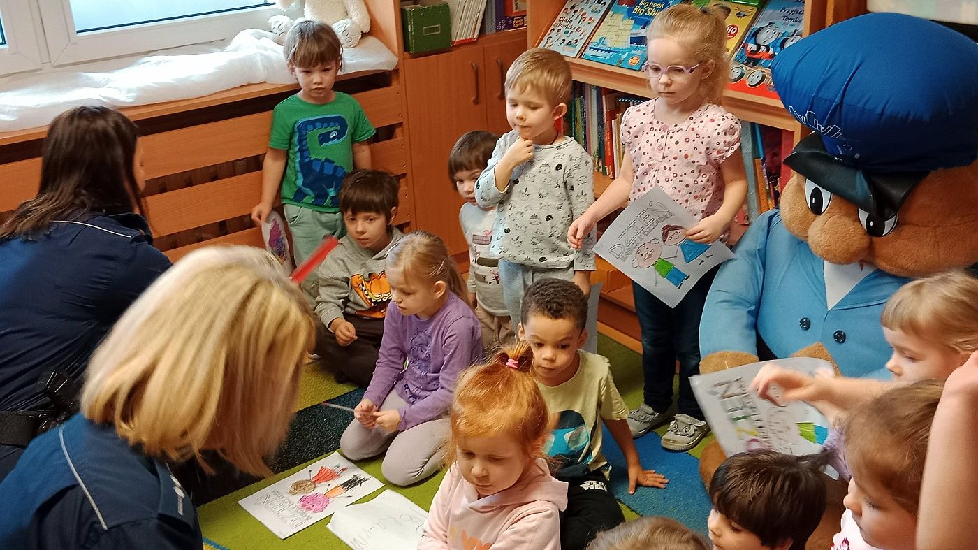 dzieci w towarzystwie funkcjonariuszek kolorują obrazki