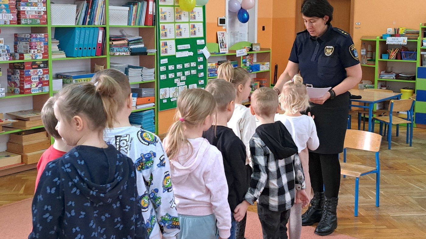 strażniczka przekazuje dzieciom obrazki do kolorowania