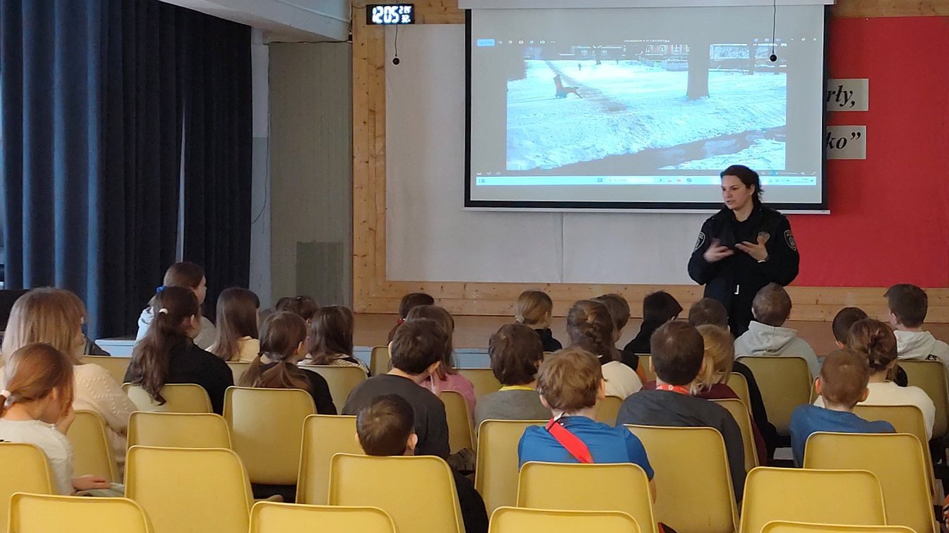 strażniczka z uczniami omawia bezpieczne zachowania na sankach ilustrowane na prezentacji