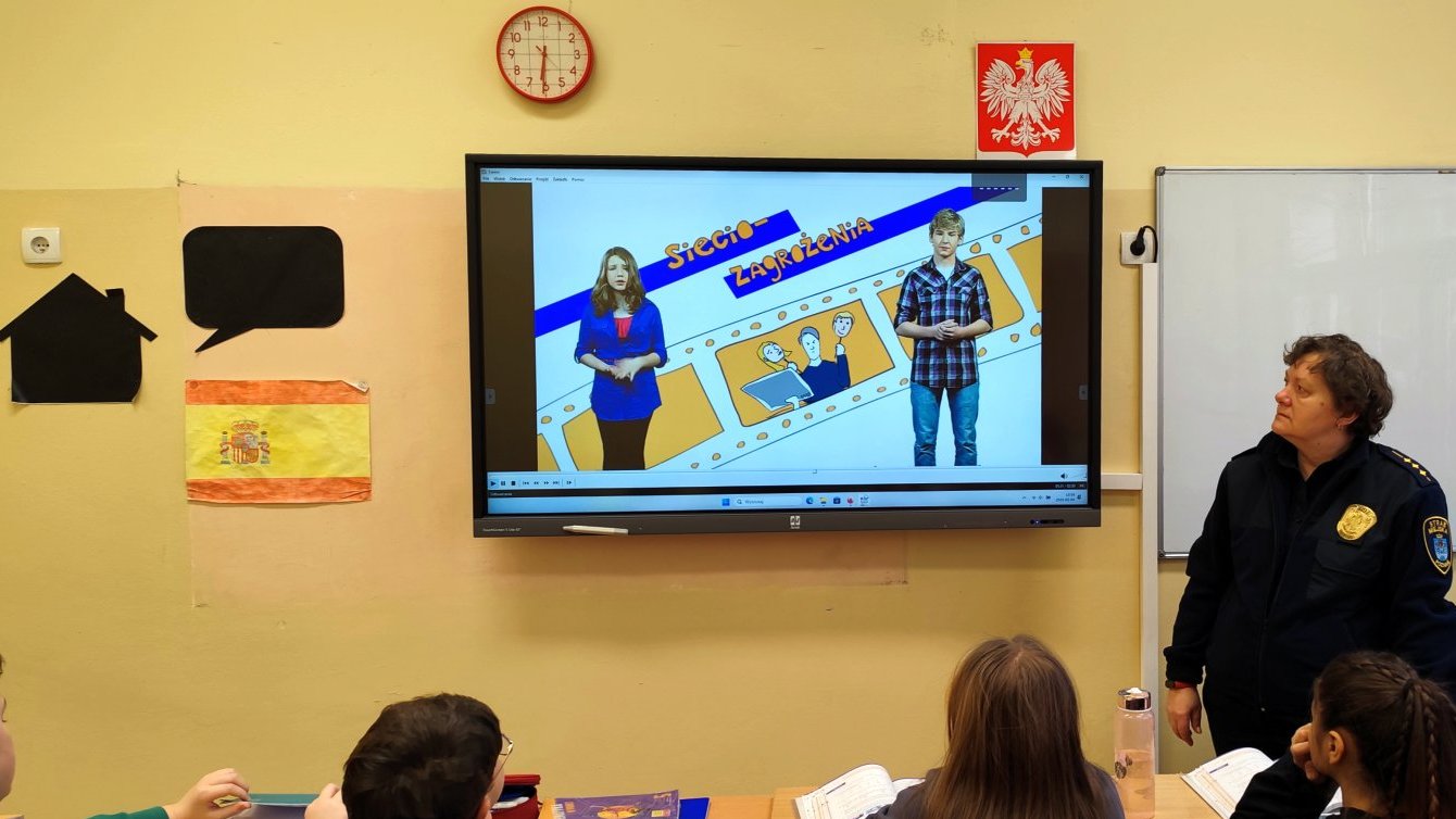 strażniczka prezentuje uczniom film o internetowych zagrożeniach