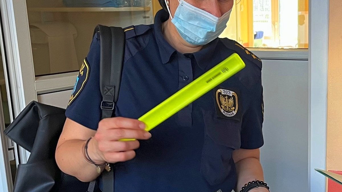 strażniczka objaśnia znaczenie odblaskowej opaski dla bezpieczeństwa pieszego