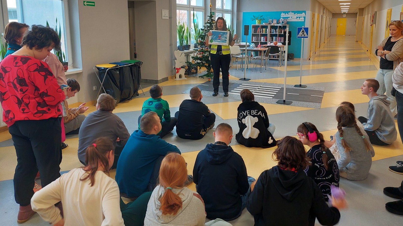 strażniczka na planszy przedstawia uczniom bezpieczne korzystanie z lodowiska