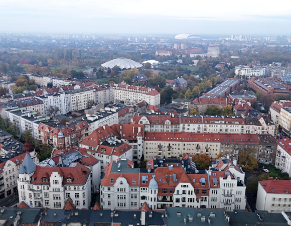 Zdjęcie dachów kamienic na Łazarzu. W tel widać Arenę