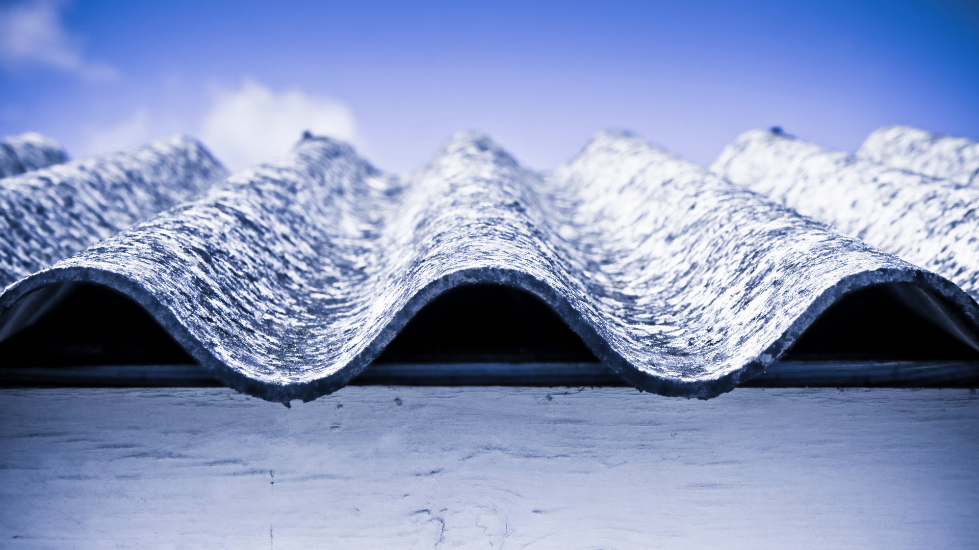 Obraz przedstawia fragment dachu zawierający azbest na tle niebieskiego nieba