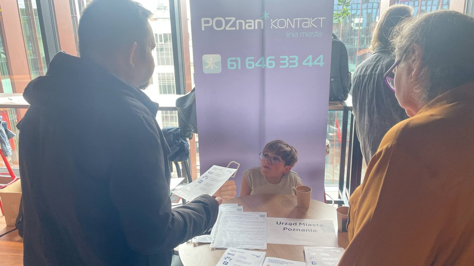 Zdjęcie przedatawia pracownika Biura Poznań Kontakt na Targach Pracy dla Osób z (Nie)pełnosprawnościami, pracownik promuje biuro na specjalnie przygotowanym stanowisku i informuje uczestników targów na czym polega nasza praca