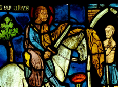 A stained-glass church window depicts Saint Martin, once a Roman soldier, sitting on his horse and cutting his cloak in half to share it with a poor man shivering from the cold. The scene symbolizes compassion and generosity - the moment when Martin chose to help someone in need.
