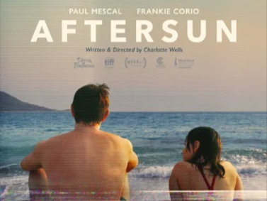 Plakat reklamujący film Aftersun, mężczyzna i dziewczynka siedzą zwróceni przodem do morza, a tyłem do widza.