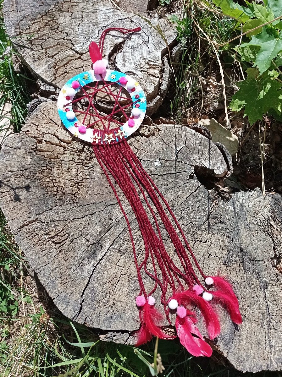 Zdjęcie Łapacza snów położone na pniu drzewa.