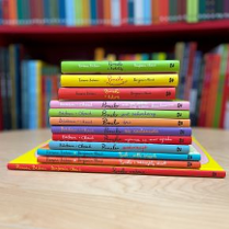 Stos kolorowych książek ułożonych na blacie.