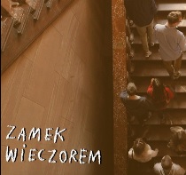 Zdjęcie przedstawia osoby zwiedzające Zamek, które wchodzą na pierwsze piętro po Schodach Paradnych. Na dole napisano białym odręcznymi literami: ZAMEK WIECZOREM.