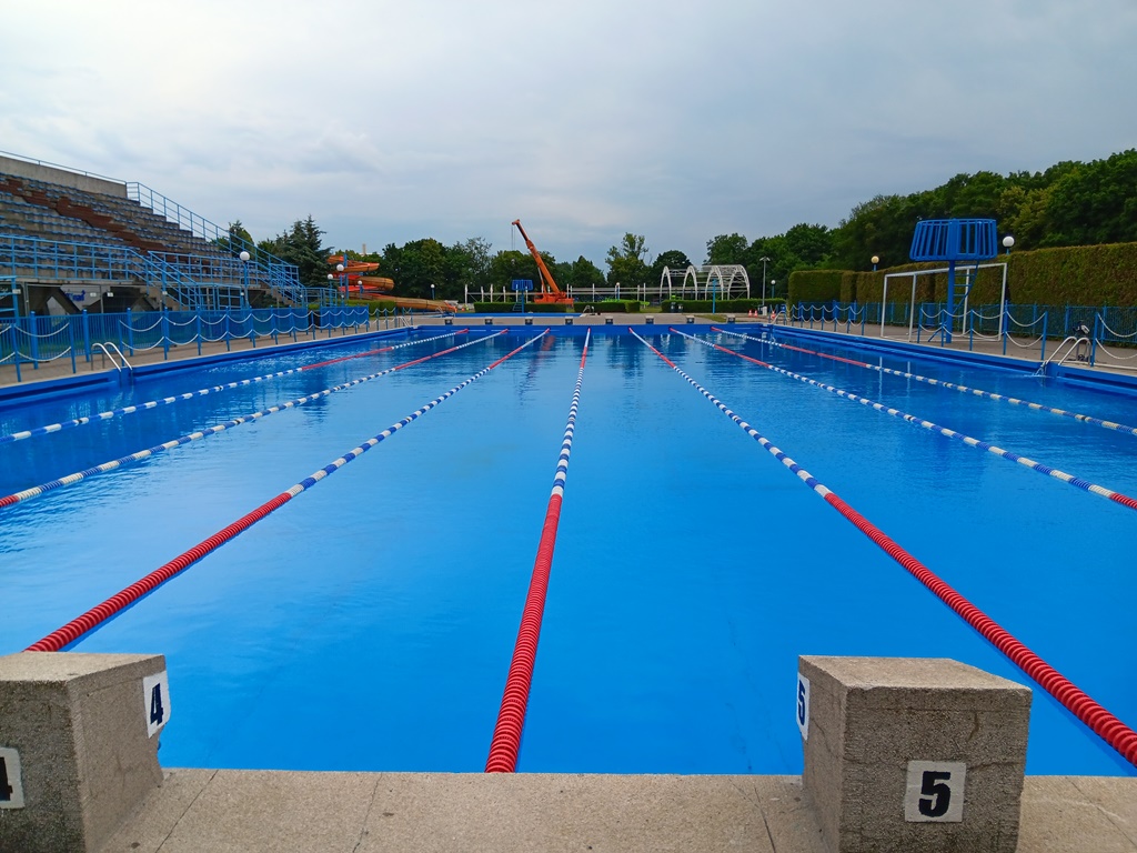 basen odkryty, widoczne tory pływackie, trybuny zielone otoczenie
