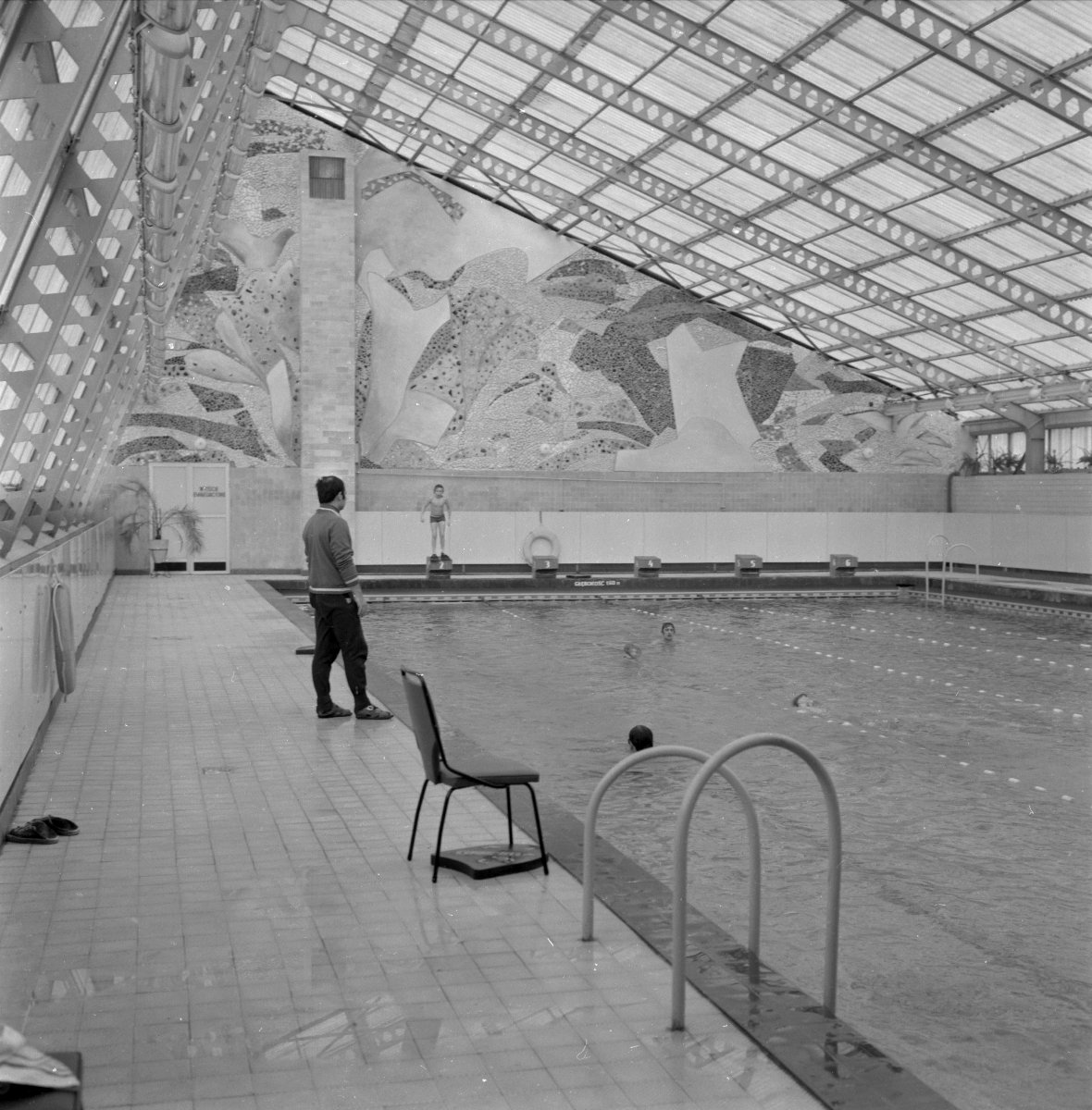 Czarno-białe zdjęcie basenu z dziećmi pływającymi w wodzie