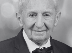 Czarno-białe zdjęcie starszego mężczyzny z siwymi włosami. Mężczyzna ma zrobione zdjęcie portretowe. Jest ubrany w garnitur i muszkę.